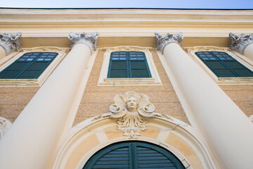 Tall columns up to the roof of the building. Yellow color in architecture. Monograms in the facade....