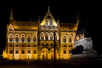 Fototapeta na wymiar Night Parliament in Budapest. Facade of the Hungarian Parliament. Illuminated in gold color. Night Budapest. Political building. Panorama of the Parliament at night. Beautiful lighting of the building