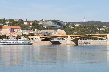 Fototapeta na wymiar Walking bridge in Budapest. Sunny weather and modern buildings in the capital. Danube river in a big city.