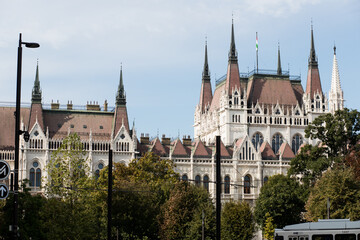 Obraz premium The tall spiers of the Parliament in Budapest. Capital of Hungary. The main attraction of Europe. Beautiful facade of the Parliament building. Burgundy roof of the building. Gothic style in architectu
