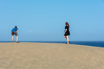 Two teenagers stand on a sand dune