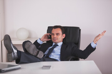 a focused businessman engages in a crucial phone call at the office in a modern workspace. He demonstrates the essence of multitasking and efficiency - 727073811