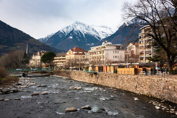 City of Merano, Italy. Panoramic view of houses along river and mountain - obrazy, fototapety, plakaty