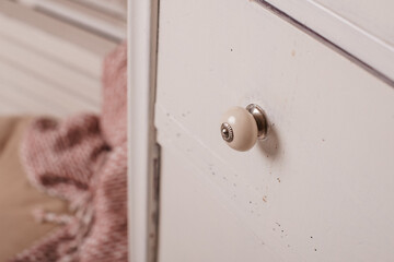 Close-up of an ivory dresser drawer, focusing on its round ceramic knob, a blend of simplicity and elegance.