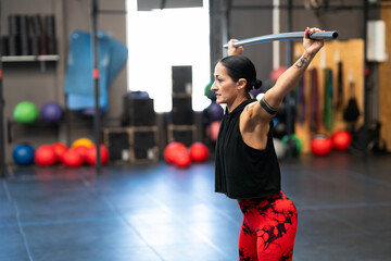 Woman warming up with a bar in a cross training gym