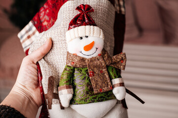 Close-up of a snowman toy being tucked into a cozy quilt, adding warmth to your winter decor.