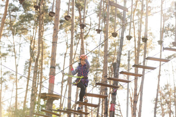 the girl in the orange helmet in the adventure Park holds on to the ropes