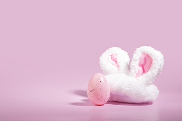 Springtime celebration, pink background, bunny ears, decorated Easter egg, joyful tradition