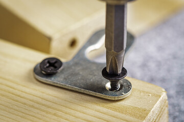 Screwing a furniture hanger to a board with a self-tapping screw