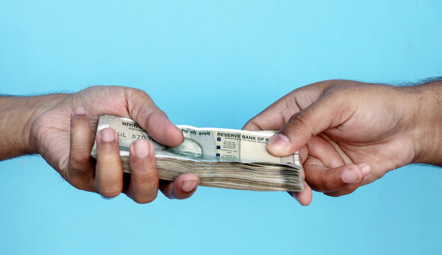 Hand Giving Indian 500 Rupee Bank Notes. concept for earnings or spend in Agriculture.