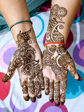 Beautiful artwork drawn on the hand of an Indian bride with herbal heena in wet condition.