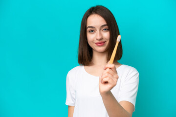 Young Ukrainian woman brushing teeth isolated on blue background with happy expression
