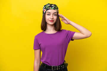 Young Ukrainian woman isolated on yellow background saluting with hand with happy expression