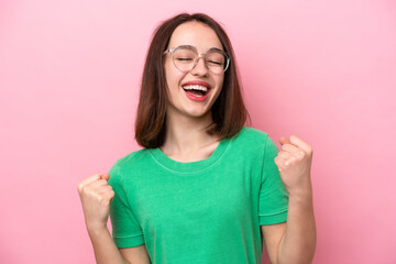 Young Ukrainian woman isolated on pink background With glasses and celebrating a victory
