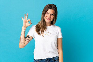 Young slovak woman isolated on blue background showing ok sign with fingers
