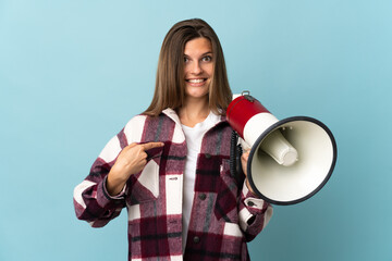Young Slovak woman isolated on blue background holding a megaphone and with surprise facial expression