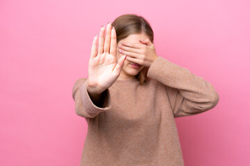 Teenager Russian girl isolated on pink background making stop gesture and covering face