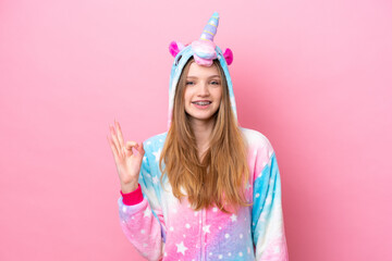 Teenager Russian girl with unicorn pajamas isolated on pink background showing ok sign with fingers