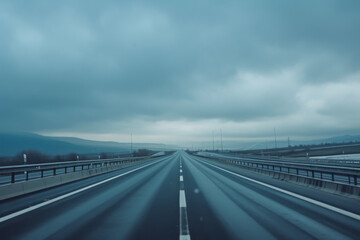 A gray cloudy sky with long stretch of highway.