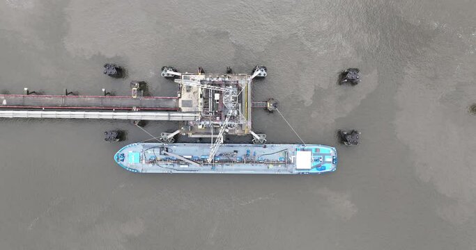 Top down view on landing port for bulk carrier ships. Oil tanking , Loading and unloading of inland waterway vessels, Homogenization and Blending Services in operation. Birds eye view.