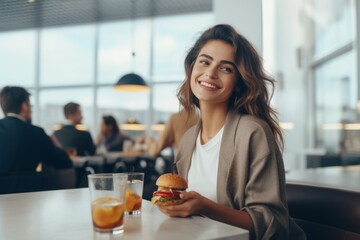 Happy woman enjoying a burger in a busy restaurant