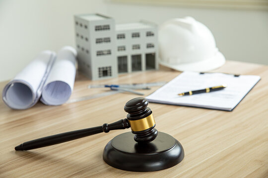 Wooden gavel, house and yellow helmet