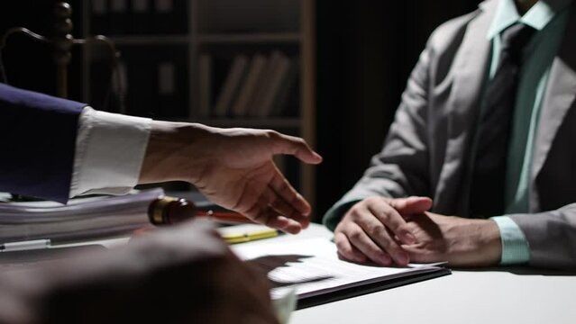 Corrupt lawyer accepts bribes from an unknown man in the dark. Businessman in the dark tries to bribe officials.