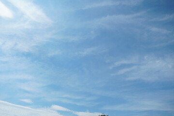 White fluffy clouds in the sky. Blue sky and cloud cover on a sunny summer day. Empty background,...