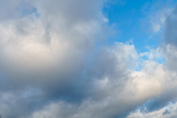 White fluffy clouds in the sky. Blue sky and cloud cover on a sunny summer day. Empty background, copy space