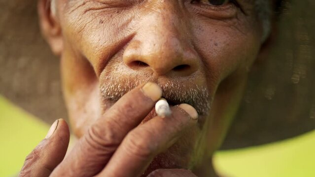 closeup of senior asian farmer smoking cigarette, low-income cultural habit asia