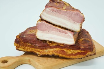 The meat dish is smoked bacon on a wooden board. The product is ready to use. White background.