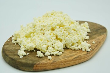 Cottage cheese on a wooden board. The product is ready to use. White background.