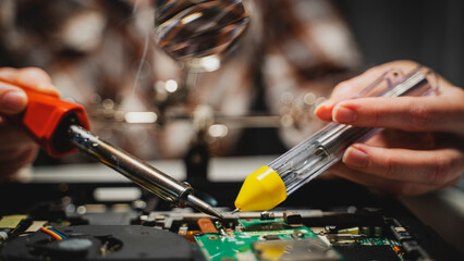 the master solders the chip with a soldering iron - obrazy, fototapety, plakaty