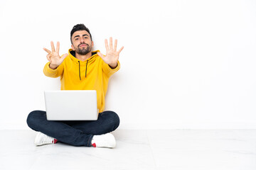 Caucasian man sitting on the floor with his laptop counting nine with fingers