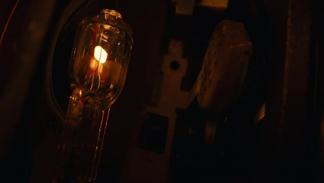 Turning off flicker 8mm film projector light bulb. Source of filmstrip illumination, projecting frames onto screen.