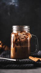 Ice cold coffee with chocolate in a glass jar on a dark background