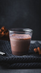 Hot chocolate with cinnamon in a glass on a black background.
