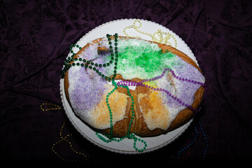 Mardi Gras king cake on a pedestal with beads