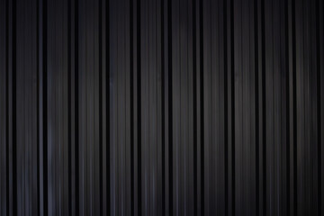 black corrugate wall background and texture,vertical black metal fence panel with light and shadow.