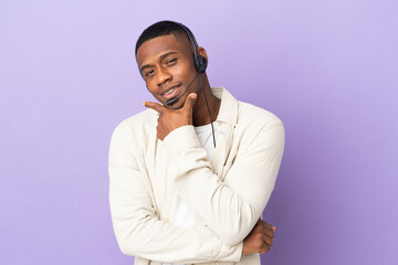 Telemarketer latin man working with a headset isolated on purple background happy and smiling