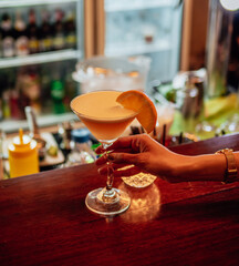 Cocktail drink on night club. Close up of cocktail served in glass decorated with lemon peel