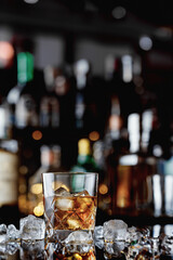 Whiskey in a glass with ice cubes. Whiskey with ice on a wooden table