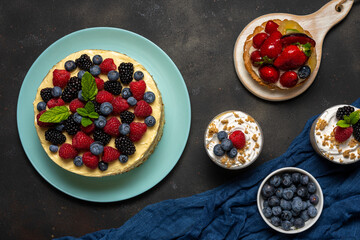 Homemade cake with fresh berries and sweet desserts on dark background.