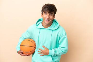 Handsome young basketball player man isolated on ocher background smiling a lot