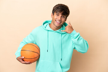 Handsome young basketball player man isolated on ocher background making phone gesture. Call me...