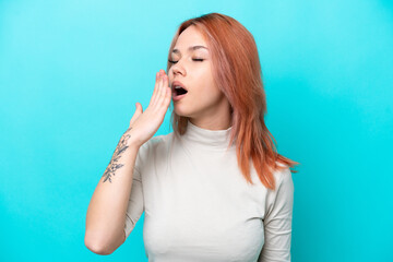 Fototapeta premium Young Russian woman isolated on blue background yawning and covering wide open mouth with hand