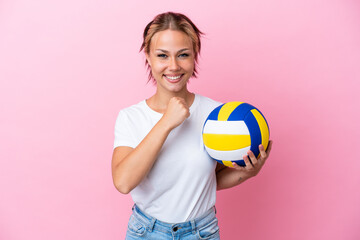 Young Russian woman playing volleyball isolated on pink background celebrating a victory