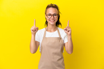 Restaurant waiter Russian girl isolated on yellow background pointing up a great idea