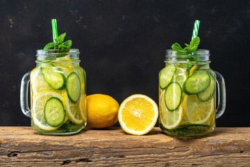 Detox water with sliced lemon and cucumber in a jar on dark background. Healthy concept.