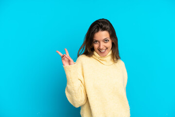 Young caucasian woman isolated on blue background smiling and showing victory sign